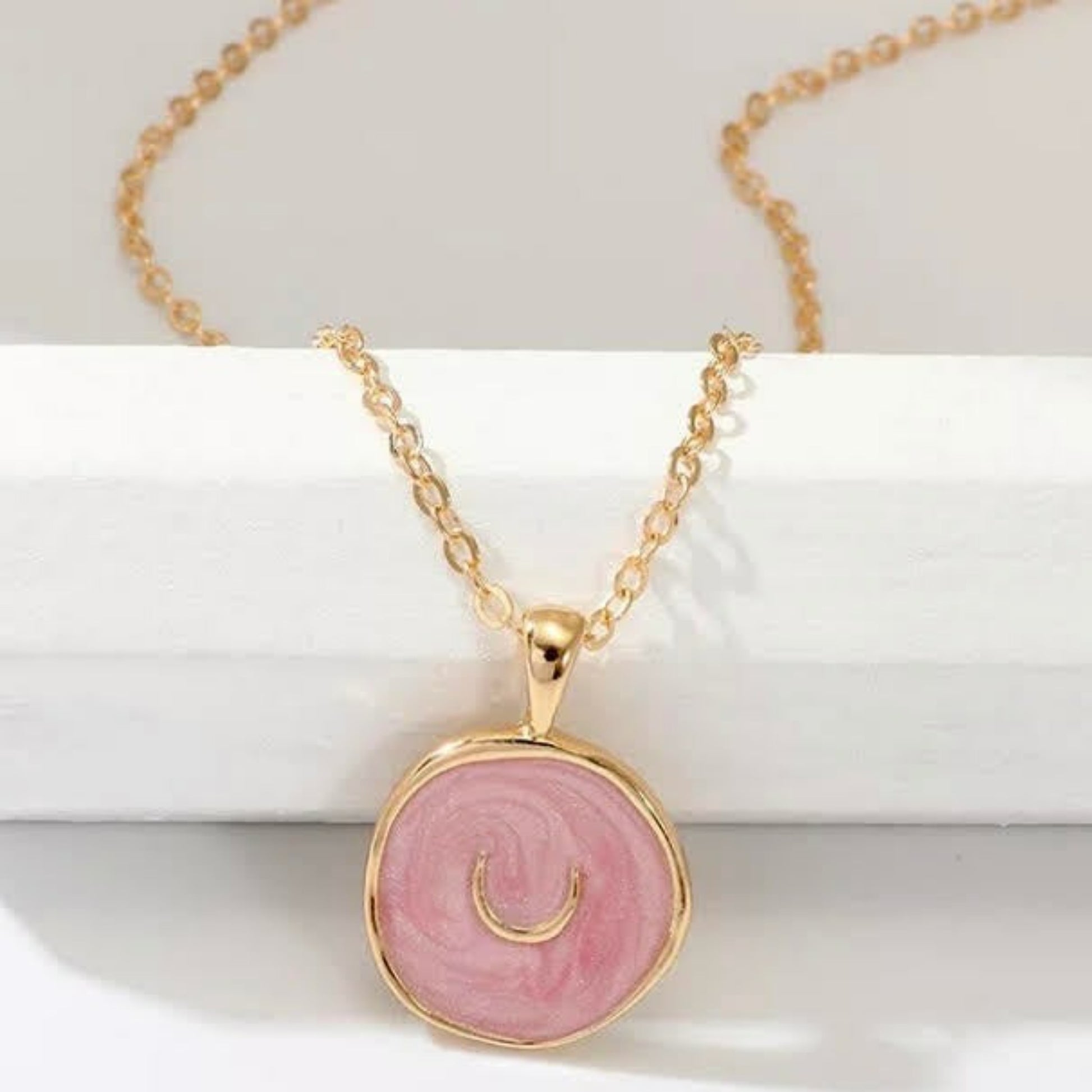 Gold necklace with pink enamel coin pendant with a crecent moon in the center