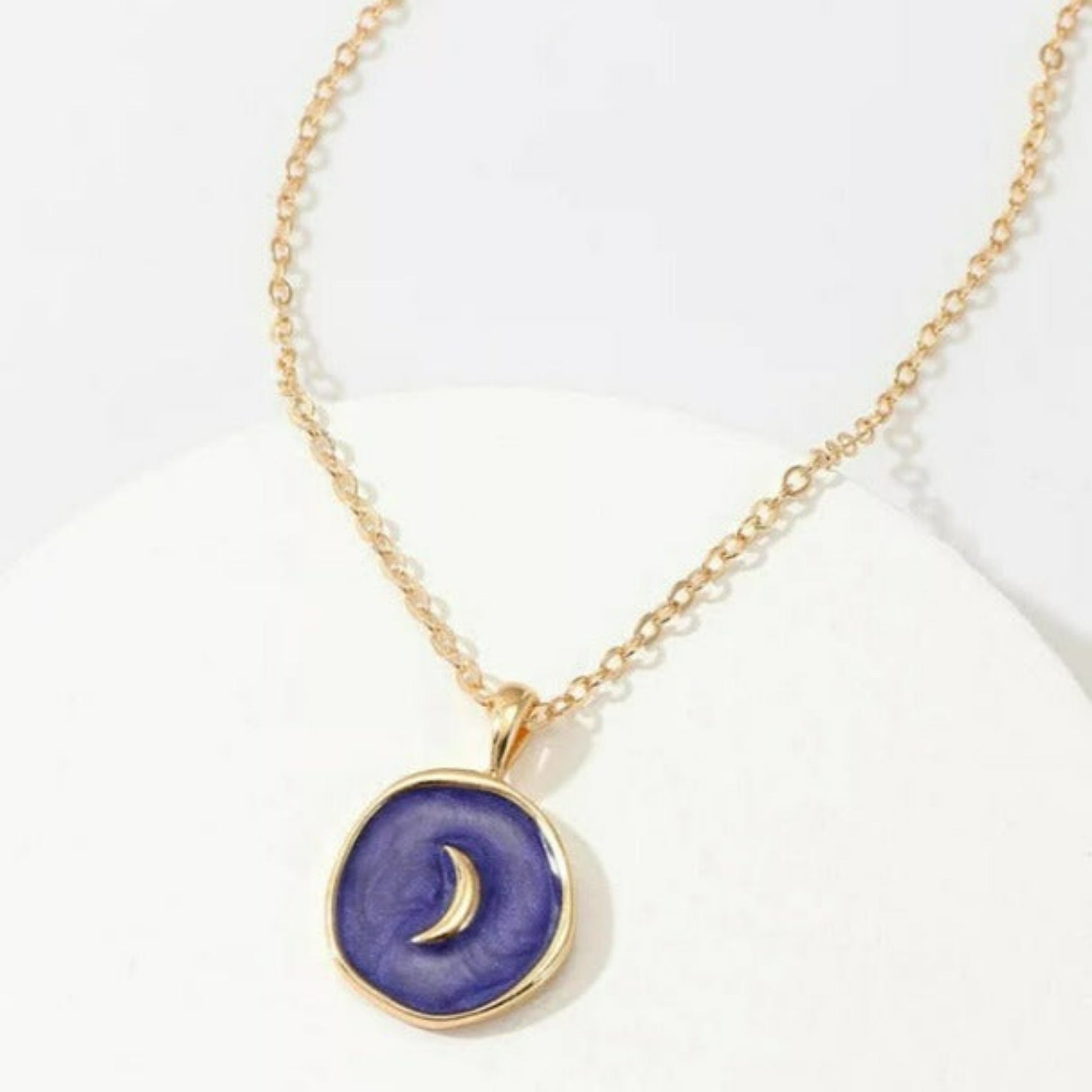 Gold necklace with a coin pendant filled in blue enamel and a gold half moon in the center 